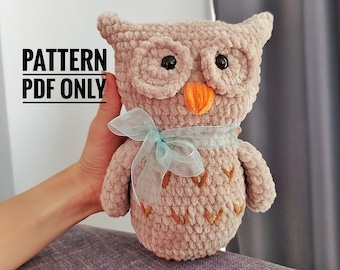 May include: A plush, beige owl with large black eyes, an orange beak, and a light blue ribbon. The owl has embroidered details and the text "PATTERN PDF ONLY" is visible.