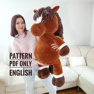 May include: A large, plush brown horse with a white blaze and mane is held up. The horse has white accents on its legs and a green eye. The text "PATTERN PDF ONLY ENGLISH" is visible in the image.