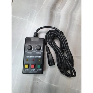 Puede incluir: Un controlador de temporizador negro con un cable de alimentación. El controlador tiene dos diales etiquetados como "Duración" e "Intervalo", y tres botones etiquetados como "Timer", "Power" y "Manual". El texto "Made in China" está impreso.