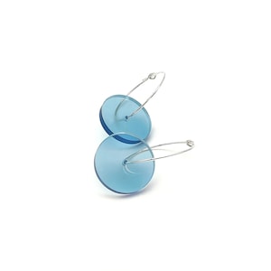 May include: A pair of silver hoop earrings with a light blue, round, translucent disc attached to each hoop.