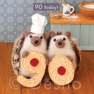 May include: Two cute hedgehog figurines wearing chef hats holding up two large cookies shaped like the number 90. The cookies have red jelly centers and are decorated with swirls. The text "90 today!" is written in black on a white background above the hedgehogs.