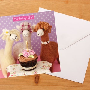 May include: A birthday card featuring three alpaca figurines with a cupcake and a single lit candle. The card has a purple background with white polka dots and the text "Birthday Girl".