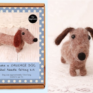 May include: A craft kit for making a felt sausage dog, with a finished size of approximately 13cm. The kit includes wool and instructions for needle felting. The box has a blue polka dot border and text that reads "Make a Sausage Dog".