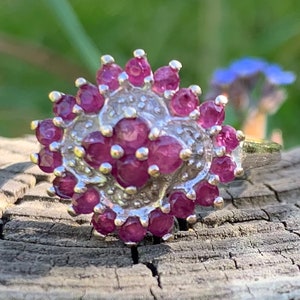 以下が含まれることがあります： 花柄のデザインにピンクのルビーの石がセットされたシルバーリングです。