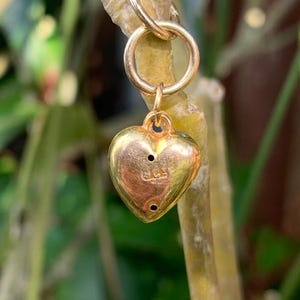 May include: A gold heart charm with a small loop at the top. The charm has a small inscription on the back that reads "925".
