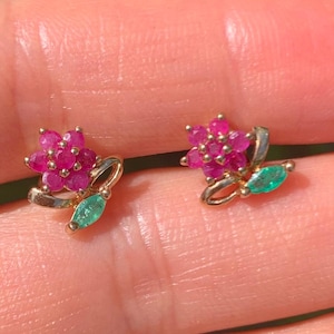May include: A pair of gold earrings with a flower design. The flowers are made of pink and red gemstones, and the leaves are made of green gemstones.