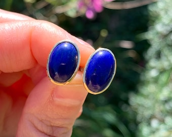 Può includere: Un paio di orecchini d'oro con pietre di lapislazzuli di forma ovale. Le pietre sono di un blu intenso.