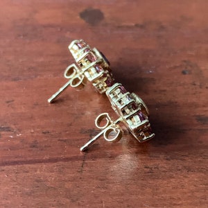 K&ouml;nnte beinhalten: Ein Paar goldene Ohrringe mit einem Cluster aus kleinen rosa und klaren Steinen. Die Ohrringe haben einen Stiftverschluss.