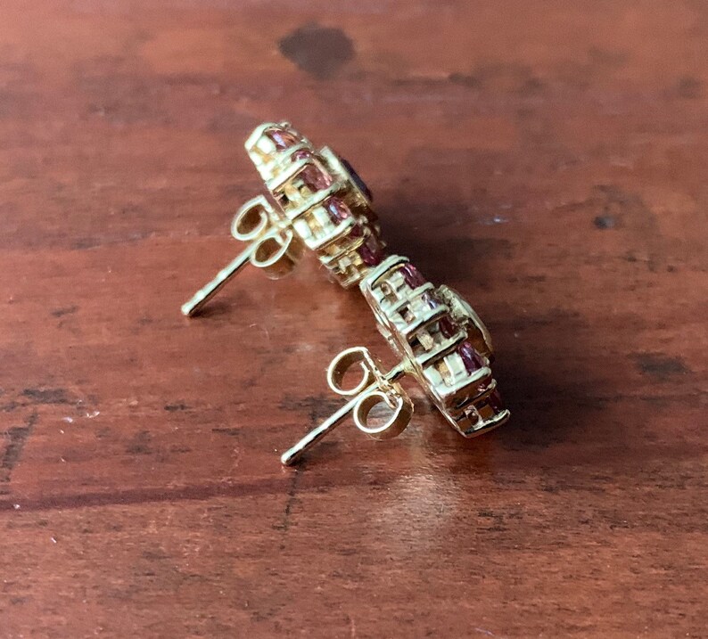 K&ouml;nnte beinhalten: Ein Paar goldene Ohrringe mit einem Cluster aus kleinen rosa und klaren Steinen. Die Ohrringe haben einen Stiftverschluss.