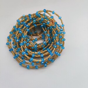 May include: A beaded waist chain with blue and gold beads. The chain is coiled up in a circle.