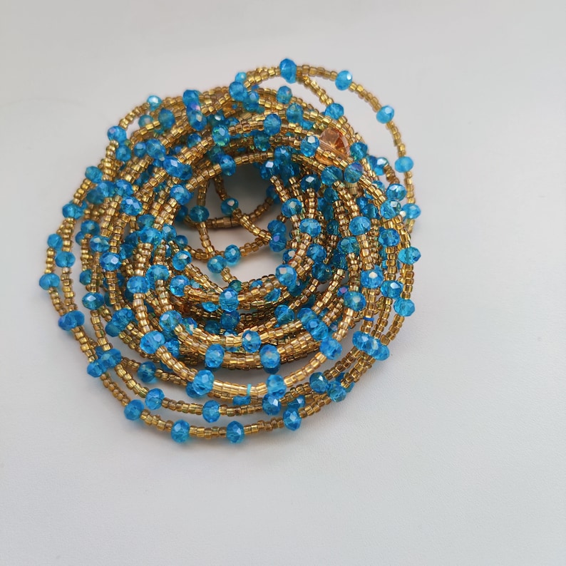 May include: A beaded waist chain with blue and gold beads. The chain is coiled up in a circle.