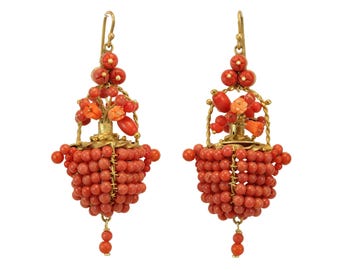 May include: A pair of coral earrings with a gold-tone metal design. The earrings feature a basket-like structure made of small, round coral beads. The top of the earrings have a cluster of coral beads and a gold hook.
