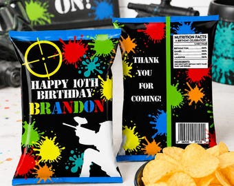 May include: Two custom chip bags with a black background, colorful paint splatters, and a yellow target graphic. The front reads "HAPPY 10TH BIRTHDAY BRANDON" with a white silhouette of a paintball player. The back reads "THANK YOU FOR COMING!"