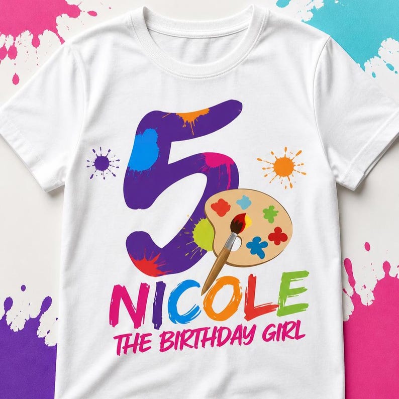 May include: White t-shirt with a colorful design for a fifth birthday. The design includes a large purple number 5 with paint splatters, a paint palette, and the text "Nicole The Birthday Girl" in bright colors.