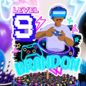 May include: A cake topper featuring a cartoon gamer wearing a VR headset and holding a controller. The design includes the text LEVEL 9 and BRANDON in bright blue, surrounded by neon-style lightning bolts, stars, and a game controller icon.
