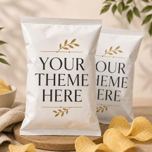May include: Two white snack bags featuring the black text YOUR THEME HERE centered on the front. Each bag is decorated with gold leaf illustrations above and below the text. The bags are positioned on a wooden surface with scattered potato chips.