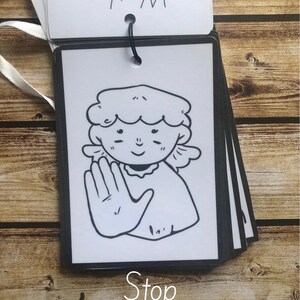 May include: Black and white illustration of a person making the sign language symbol for "stop". The image is on a white card with a black border and the word "Stop" written below the image. The card is part of a set of cards with the words "What?" and "This sign is useful when" written on the top card.