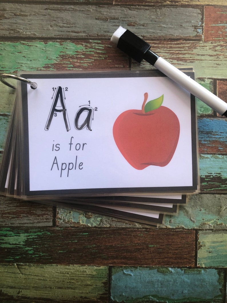 May include: A white card with black borders shows the letter 'A' with dotted lines for tracing. The letter 'A' is followed by the lowercase letter 'a' and the text 'is for Apple'. A red apple with a green leaf is illustrated to the right of the text.