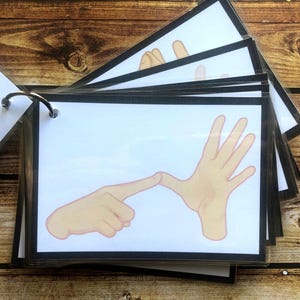May include: A set of flashcards with black borders and white backgrounds. Each card features a different hand sign, with the text "Language to learn" on the cover.