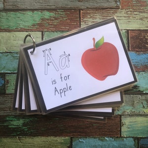 May include: A set of flashcards featuring a red apple and the letter A with dotted lines for tracing. The text "A is for Apple" is printed below the letter.