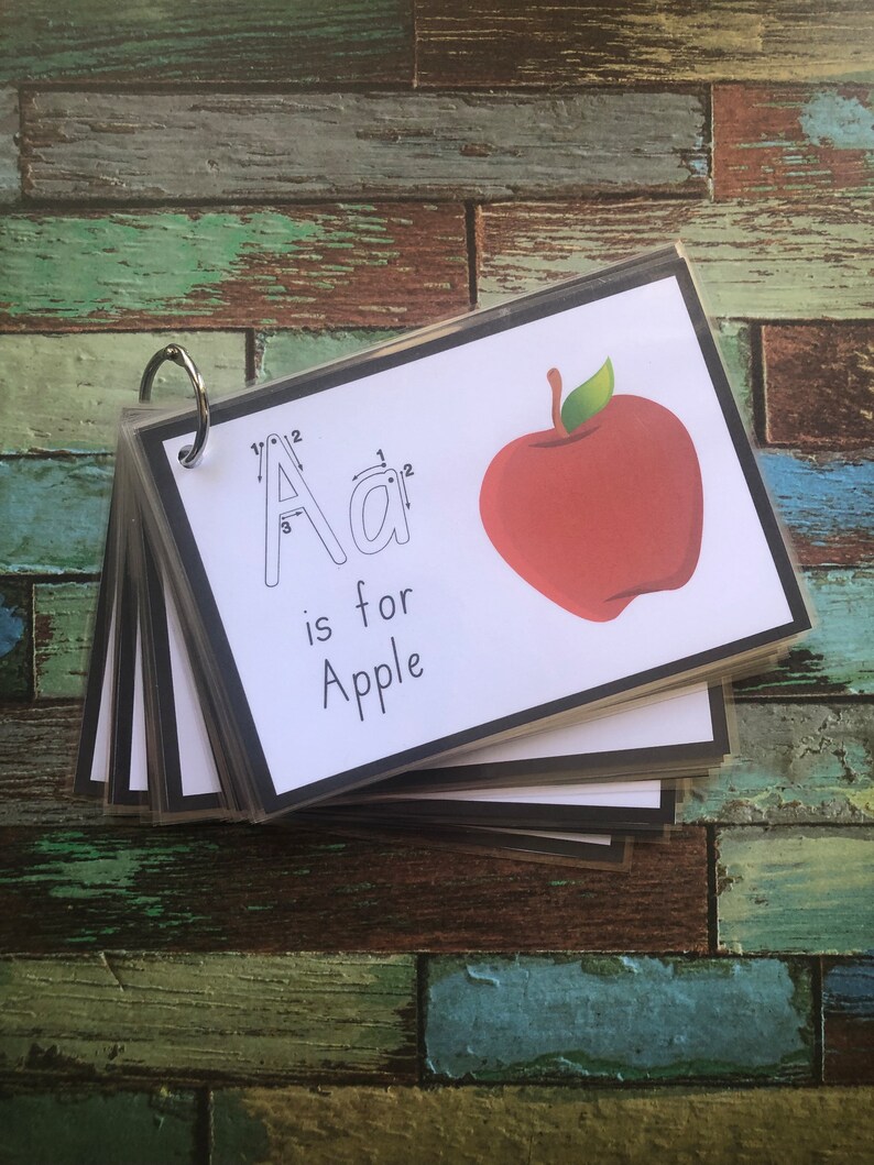 May include: A set of flashcards featuring a red apple and the letter A with dotted lines for tracing. The text "A is for Apple" is printed below the letter.