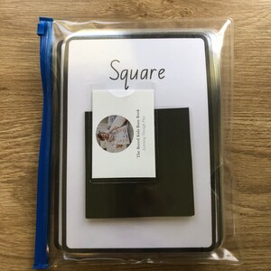 May include: A white plastic bag with a zipper closure contains a white card with the word "Square" written in black. The card is attached to a black square piece of paper. The card also has a smaller card attached to it with the text "The Bored Kids Busy Book Learning Through Play".