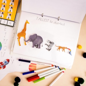 Op de afbeelding: Een witte pagina met de woorden "TALLEST to shortest" erop geschreven. Er zijn vijf dierensilhouetten op de pagina: een giraffe, een olifant, een zebra, een luipaard en een toekan. De dieren zijn gerangschikt van groot naar klein.