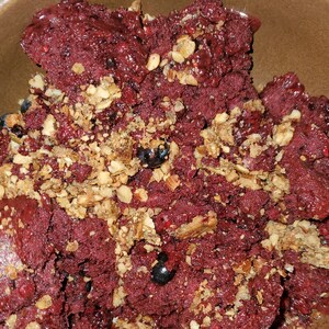 May include: A close-up of a bowl of red smoothie topped with granola and blueberries.