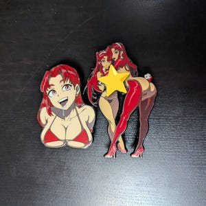 May include: Two enamel pins featuring an anime-style character with long red hair. One pin shows a bust portrait in a red bikini top. The second pin depicts a full-body figure in a red bodysuit, high heels, and a bunny tail, with a yellow star icon.