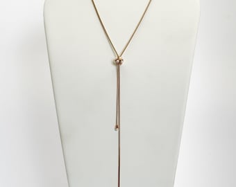 Puede incluir: Un collar dorado con un colgante de racimo de perlas y dos perlas colgantes. El collar se muestra en un busto de maniquí blanco.