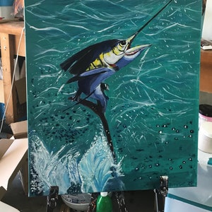 May include: Acrylic painting of a marlin leaping from teal water. The fish is depicted with blue, black, and yellow hues, with its long bill pointed upwards. White brushstrokes create the illusion of waves and splashes.