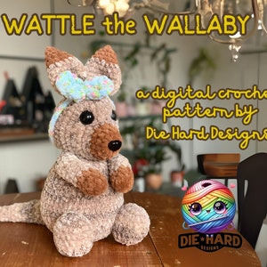 May include: Wattle the Wallaby, a digital crochet pattern by Die Hard Designs. A crocheted brown wallaby with a blue bow sits on a wooden table. The wallaby has a brown nose and black eyes. The pattern is available for purchase.