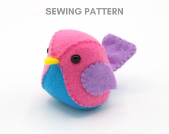 Pode incluir: Um padrão de costura para um pássaro de feltro rosa, azul e roxo. O padrão inclui instruções para fazer um pequeno pássaro de pelúcia com uma asa.