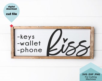 May include: A white wooden sign with black text that reads "keys, wallet, phone" and "kiss" with a small heart above the "s".