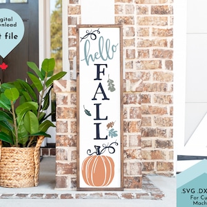Puede incluir: Un letrero vertical de madera con fondo blanco y marco de madera oscura. El letrero presenta el texto "hello FALL" en letras azules y negras, decorado con pequeñas ilustraciones de hojas y una gran calabaza naranja en la parte inferior.