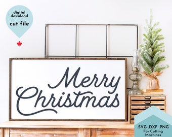 May include: A wooden framed sign with the words "Merry Christmas" in a cursive font. The sign is white with dark blue lettering. A small Christmas tree and decorative items are on a wooden cabinet next to the sign. The image also includes text that says "digital download cut file".