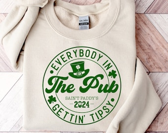 May include: A beige sweatshirt with a green circle graphic that says "Everybody in The Pub Saint Paddy's -2024- Gettin' Tipsy."