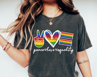 May include: A dark grey t-shirt with a peace sign, heart, and equality sign in rainbow colors. The text "peace love equality" is printed below the symbols.