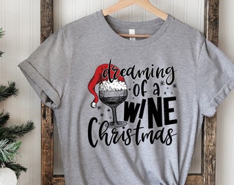 May include: Gray t-shirt with a black and white graphic of a wine glass with a Santa hat. The text on the shirt reads "dreaming of a wine christmas".