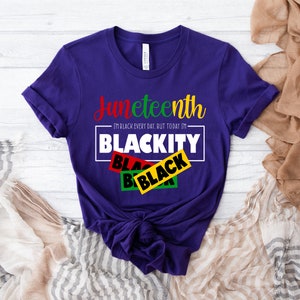 May include: Purple t-shirt with the text "Juneteenth I'm Black every day, but today I'm Blackity" in white with black, red, green, and yellow tape over the word "Black".