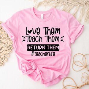 May include: Pink t-shirt with black text that reads "Love Them = Teach Them = Return Them #teacherlife".