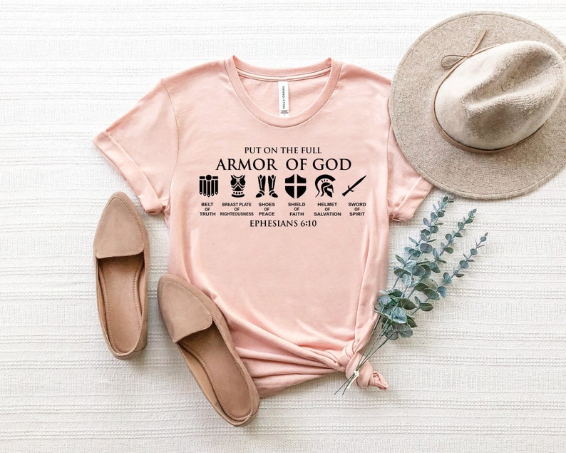 May include: A pink t-shirt with the text "Put on the full Armor of God" and a graphic of the armor of God with the text "Ephesians 6:10".