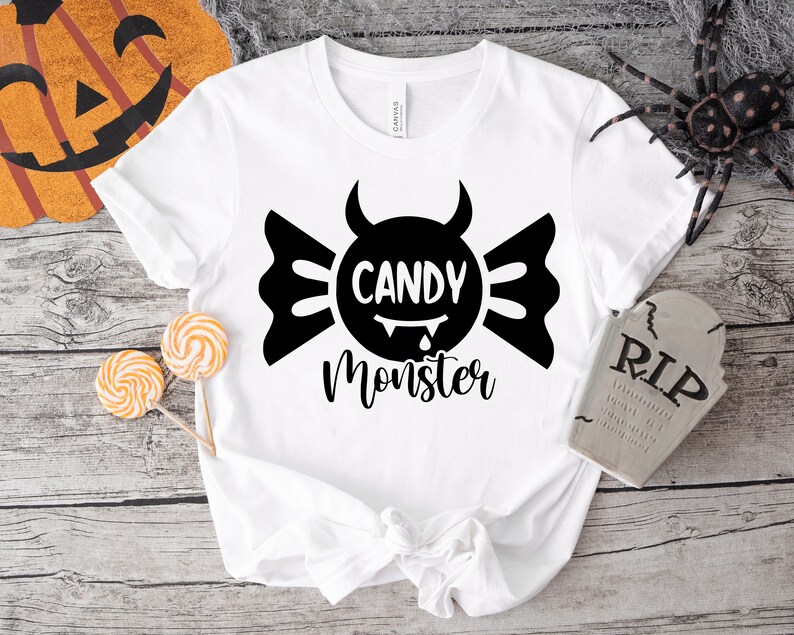 May include: White t-shirt with a black graphic of a candy with devil horns and the text "Candy Monster".