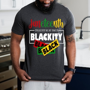 May include: A dark grey t-shirt with the text "Juneteenth I'm Black Every Day, But Today I'm Blackity" in white. The text "Blackity" is in a box with three overlapping black, yellow, and green rectangles with the word "Black" in each.