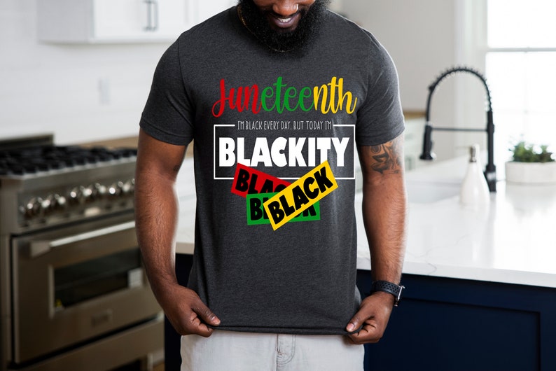 May include: A dark grey t-shirt with the text "Juneteenth I'm Black Every Day, But Today I'm Blackity" in white. The text "Blackity" is in a box with three overlapping black, yellow, and green rectangles with the word "Black" in each.