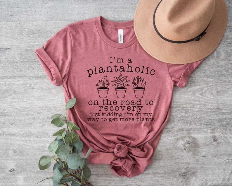 May include: A pink t-shirt with the text "I'm a plantaholic on the road to recovery just kidding, I'm on my way to get more plants".