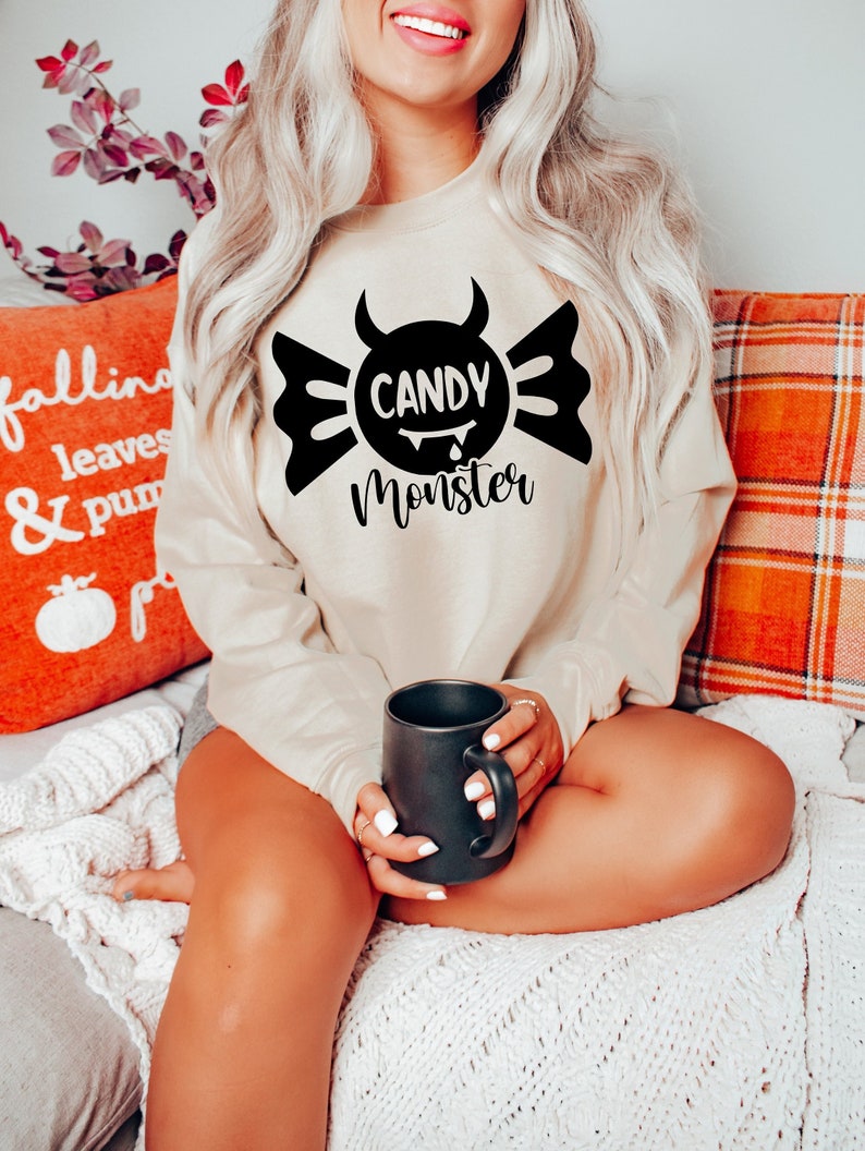 May include: A beige sweatshirt with a black graphic of a candy with horns and the text "Candy Monster".