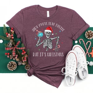 May include: A maroon t-shirt with a skeleton holding a mug and the text "When you're dead inside but it's Christmas".
