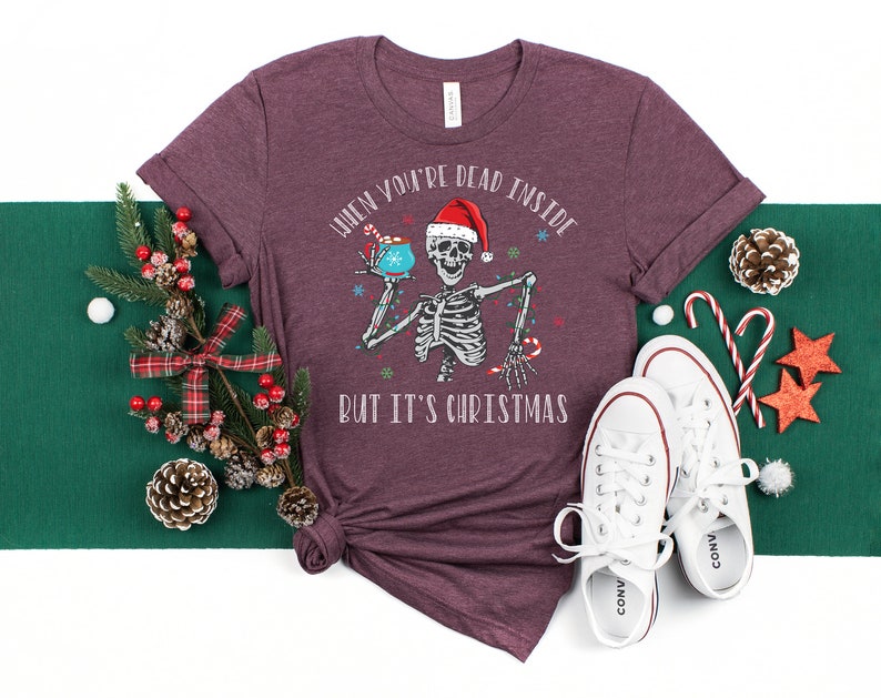 May include: A maroon t-shirt with a skeleton holding a mug and the text "When you're dead inside but it's Christmas".