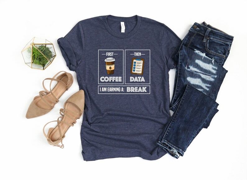 May include: A navy blue t-shirt with a white graphic that says "First - Coffee, Then - Data, I am earning a: Break". The graphic includes a cartoon image of a cup of coffee and a clipboard.